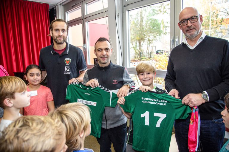 Trikots und Turnbeutel für die kleinen Handballer überreichten Silvio Heinevetter und Bob Hanning von den Füchsen Berlin und Jörg Franzen von der GESOBAU (v. l. n. r.).