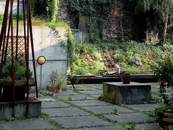 Idyllische Gartenansicht der Bibliothek Luisenbad mit lesenden Menschen