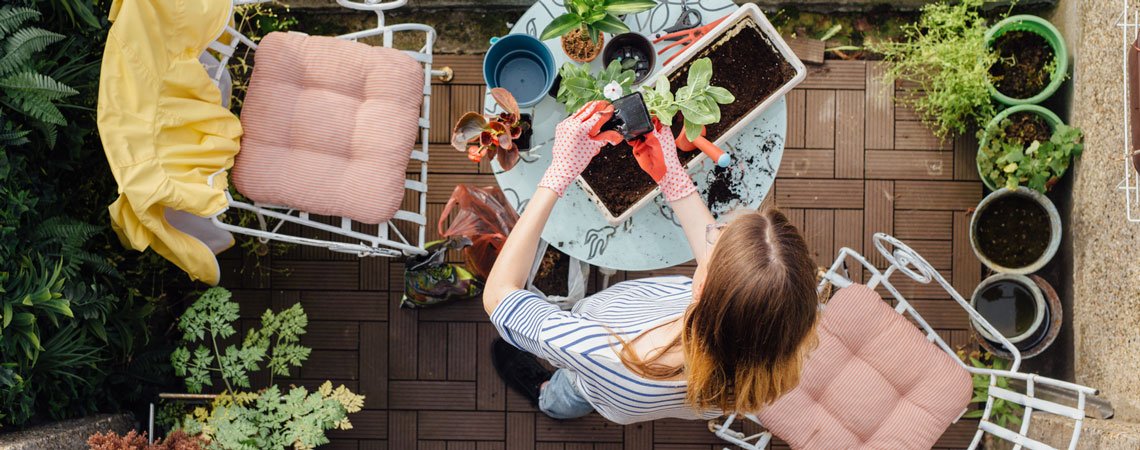 Frau gärtnert auf ihrem Balkon