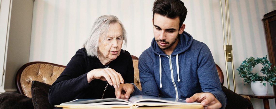 Seniorin und junger Mann schauen Fotoalbum an